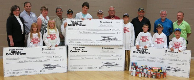 Community members holding fundraising cheques from the Youth Hockey Skills Competition